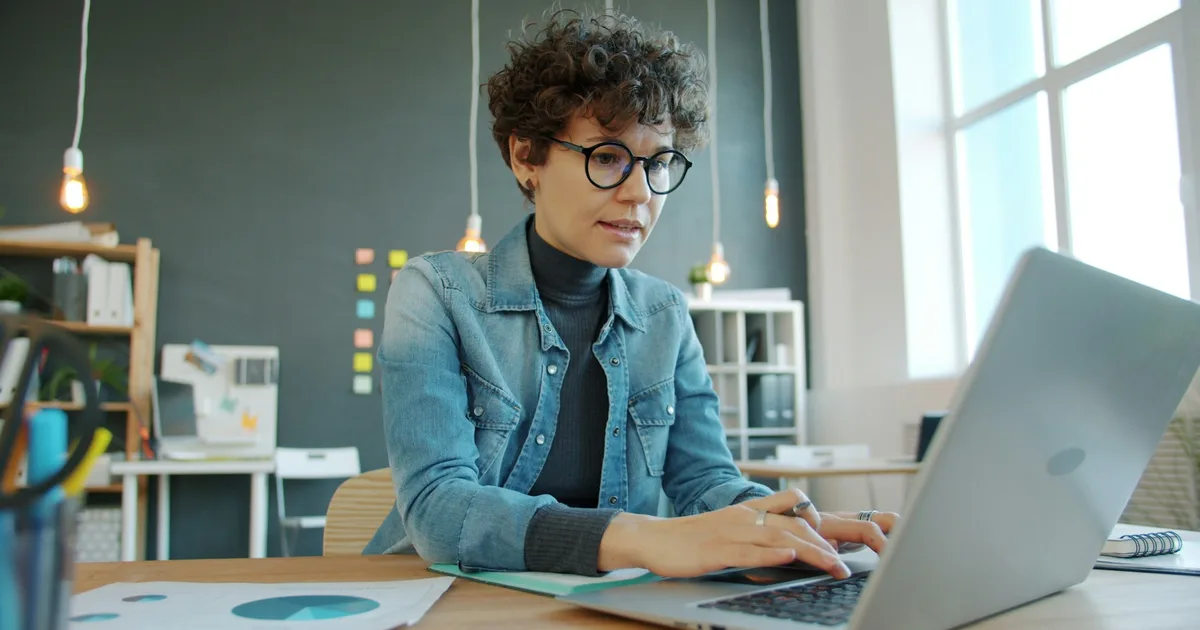 A person working on a laptop in a focused office setting