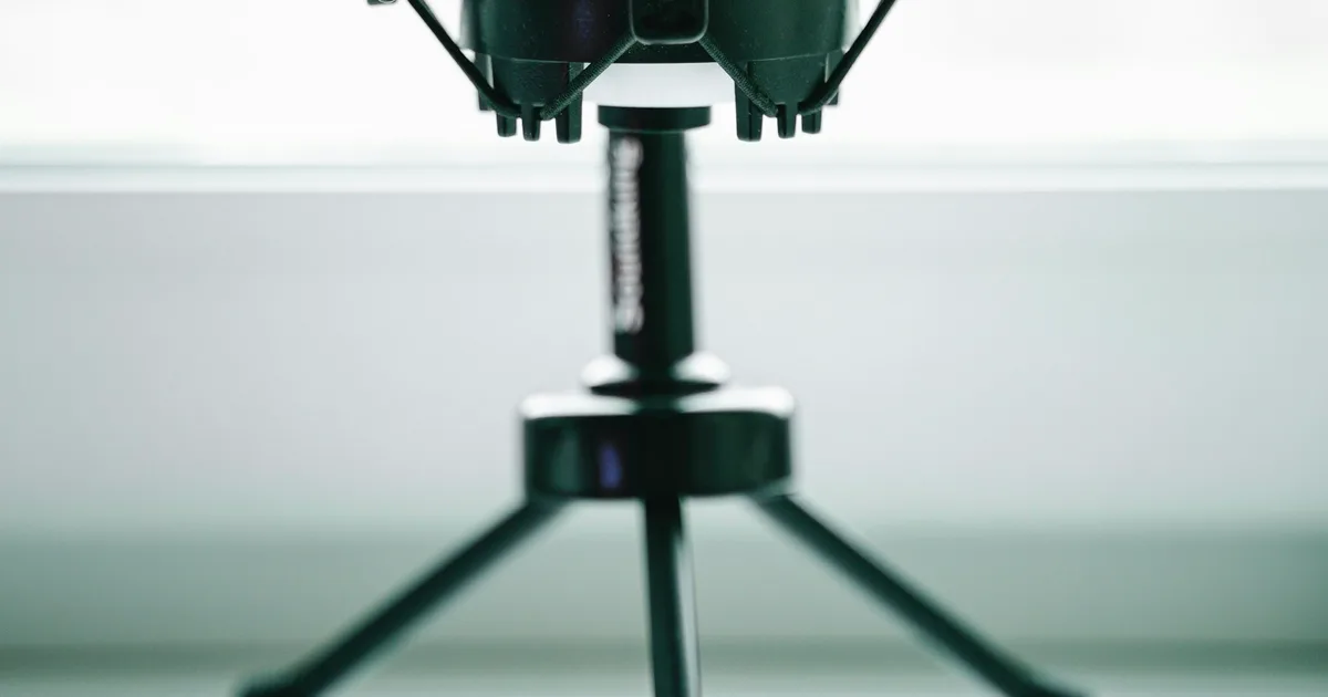 A podcast microphone on a desk beside a laptop in daylight