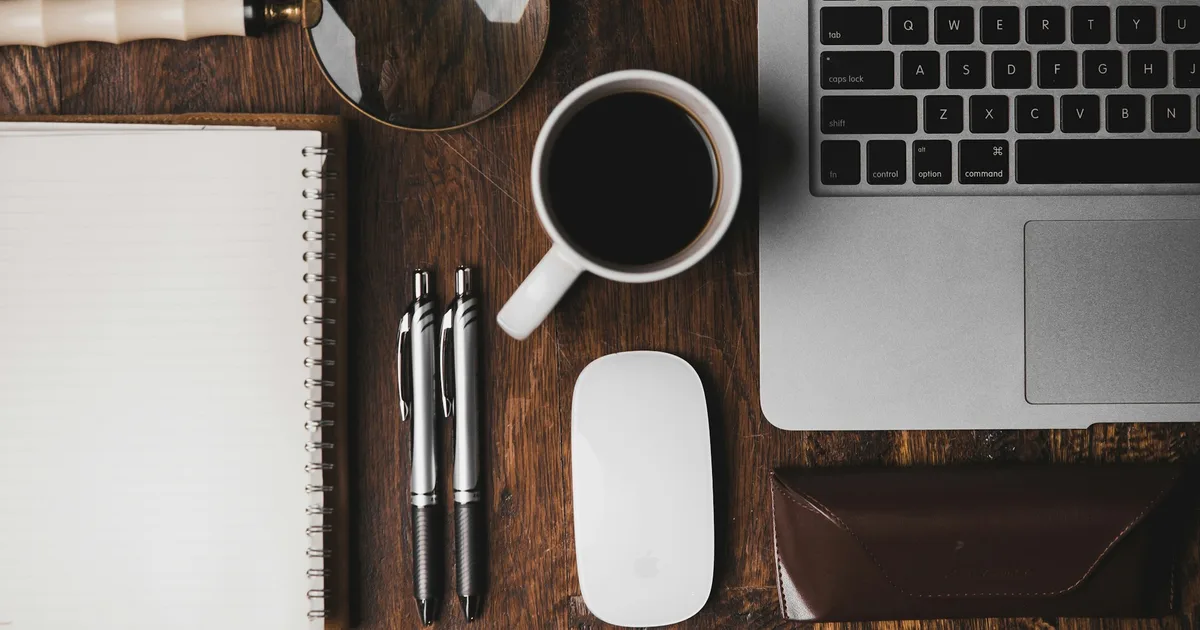 Handwritten notes on a desk beside a laptop and coffee