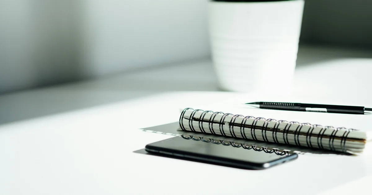 An organised desk with a phone, notebook and folders