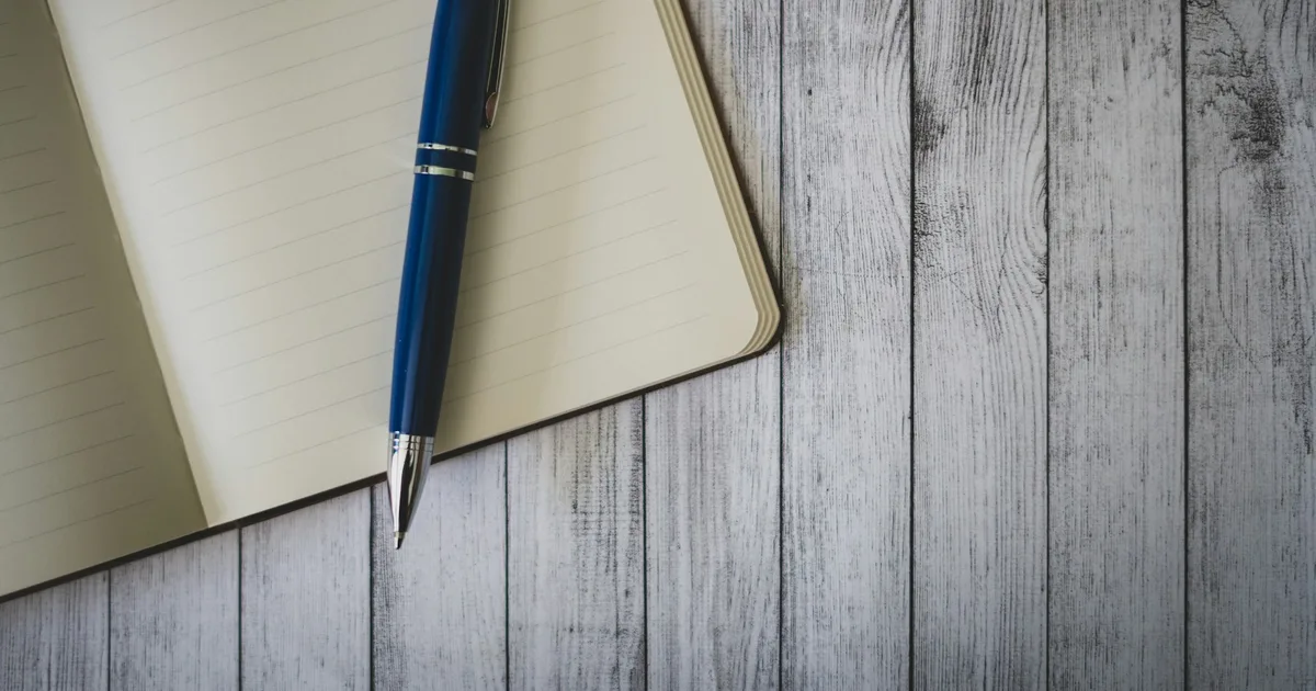 A notepad and pen being written on at a meeting desk