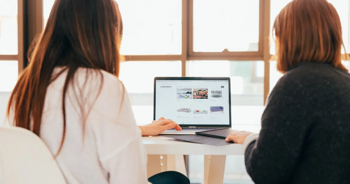 Two people talking while looking at a laptop together