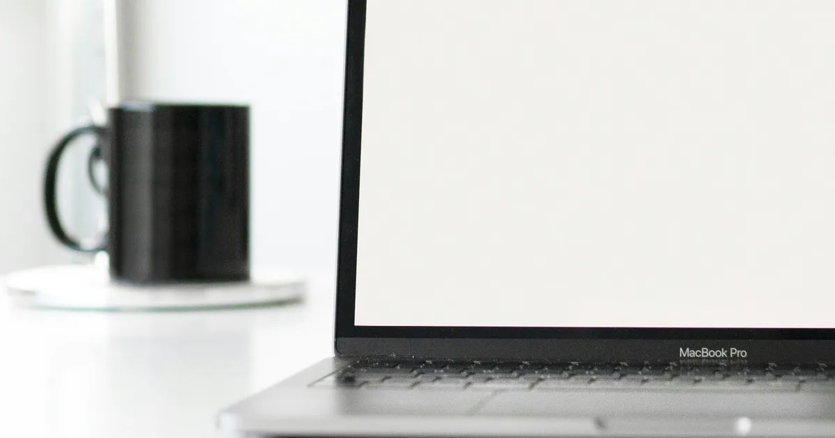 An open laptop and notebook on a bright workspace with coffee