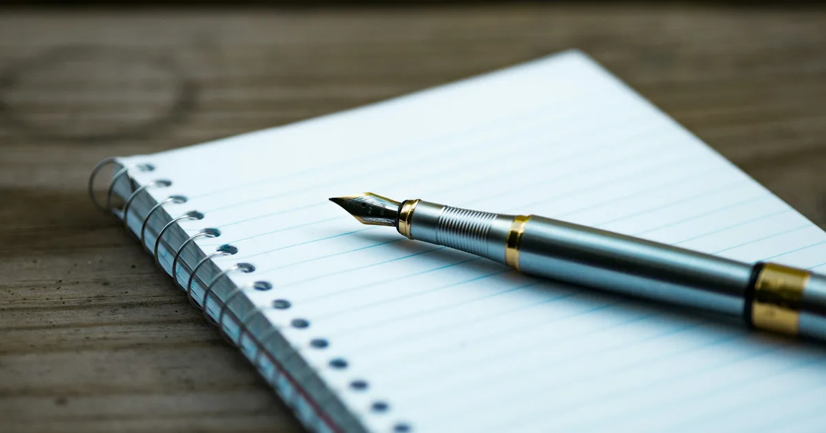 A pen writing on a lined notebook, close up