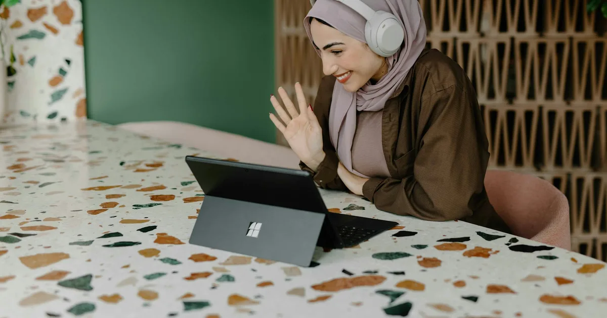 An office worker wearing a headset during a laptop video meeting