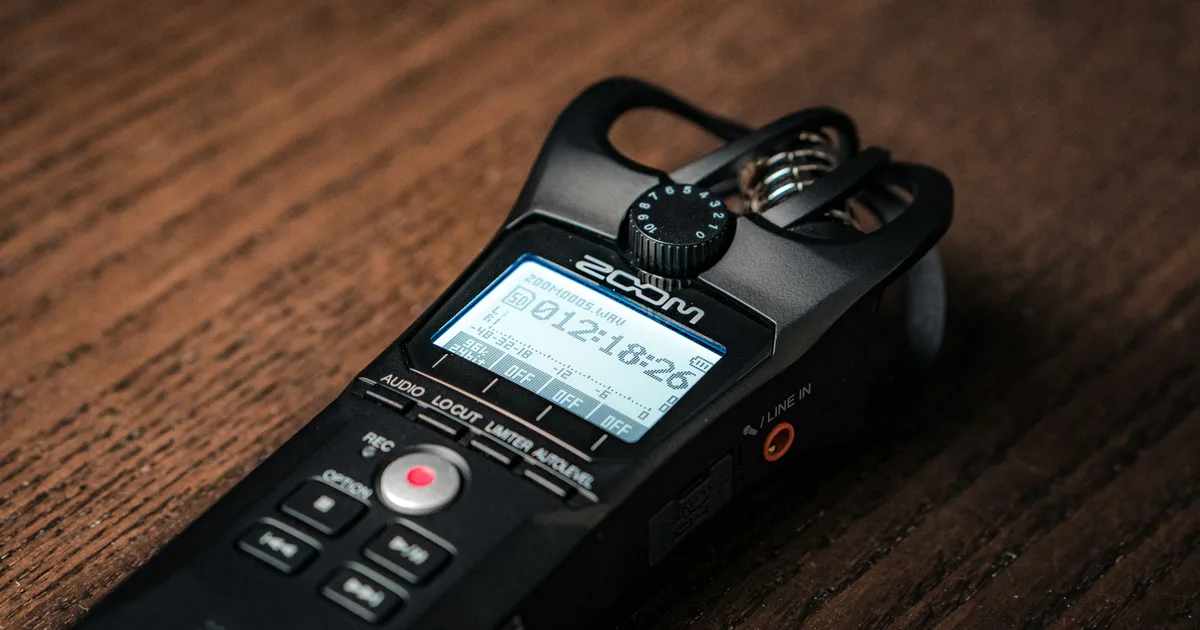 A handheld audio recorder and microphone on a desk